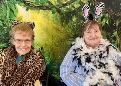 Two residents wearing animal print accessories in front of a jungle backdrop