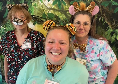Three staff members wearing animal print accessories in front of a jungle backdrop
