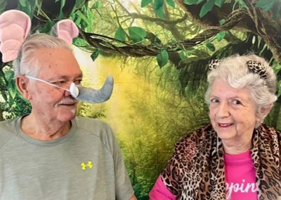 A senior couple wearing animal ears in front of a jungle backdrop