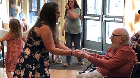 A caregiver dancing with a resident in a wheelchair