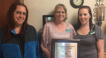 Three caregivers with an framed award