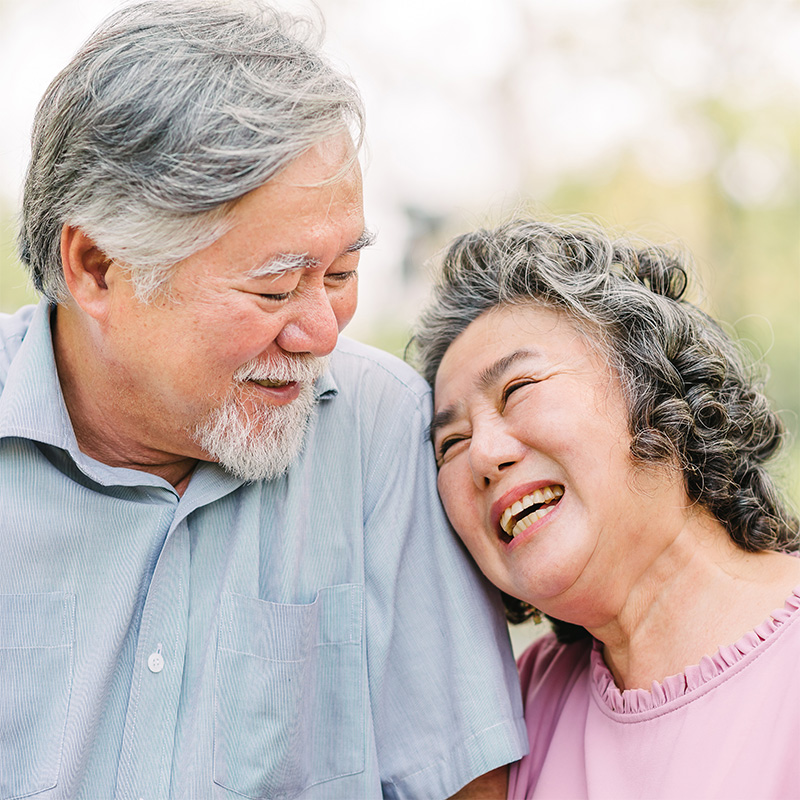 A senior couple smiling outside together.