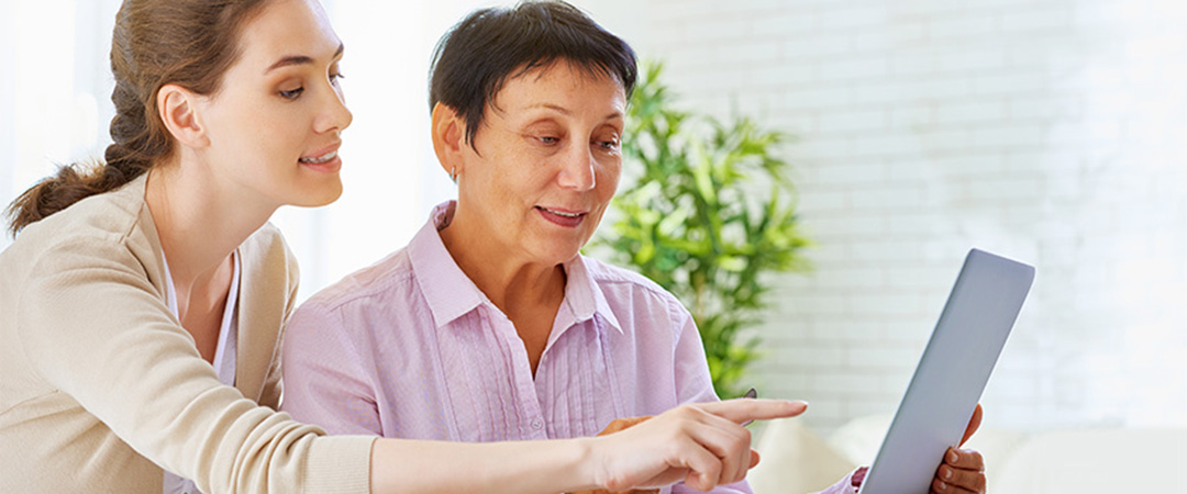 A senior woman and a younger woman looking at a laptop together.