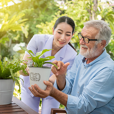 An elderly man and a younger woman looking at a plant