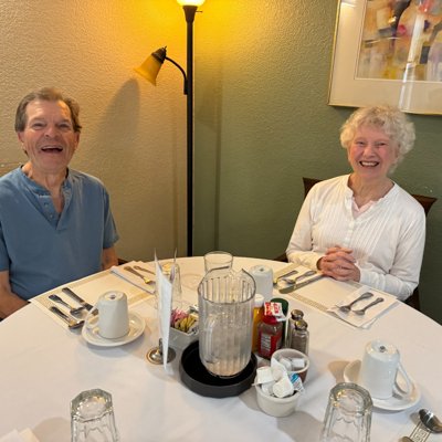 Man and woman at the dining table set with white tablecloth and full place settings.