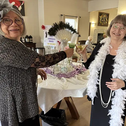 Two mature women, dressed up in party accessories, toast glasses