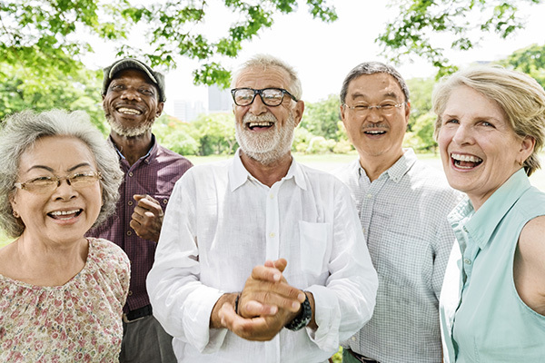 A group of mature adults under a tree laughing and talking.