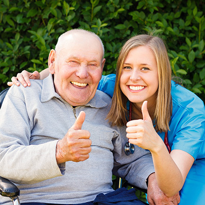 A mature male and a nurse outside holding thumbs up.