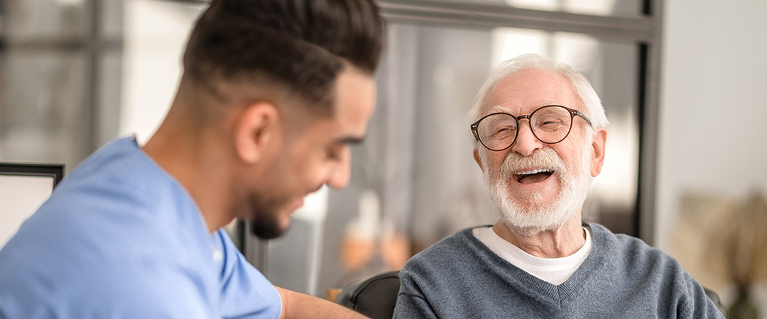 A senior man smiling with a skilled nurse.