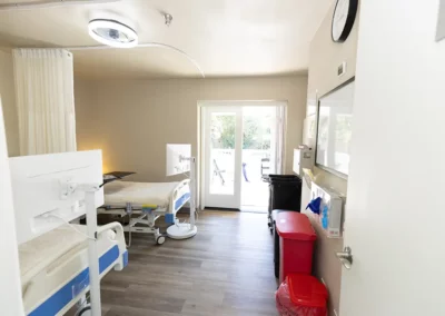 A patient room with two beds and a large sliding glass door