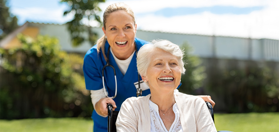 A nurse and patient going for a stroll outdoors.