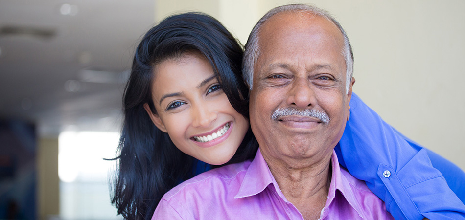 A father and daughter smiling together outside.