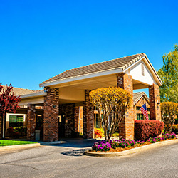 Front of Oakwood Village Assisted Living Community with driveway and porte-cochère