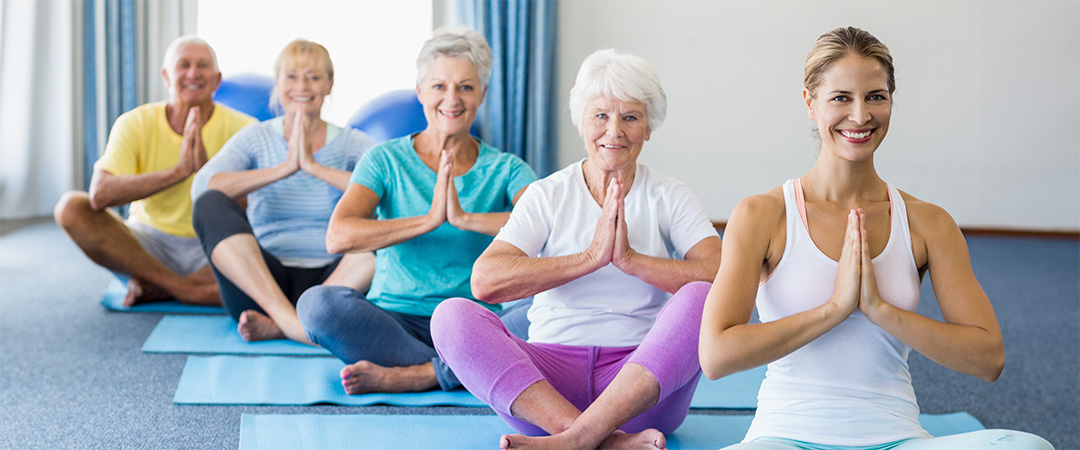 Yoga instructor and four participants on mats in prayer position