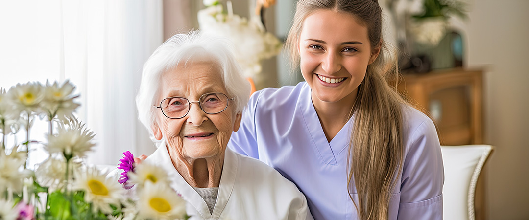 Elderly woman and healthcare worker with daisies in the foreground.