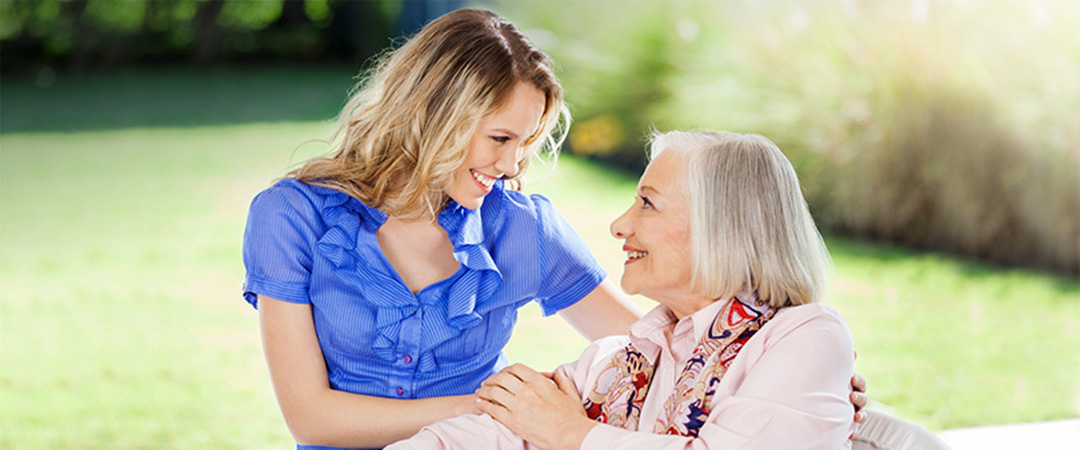 An elderly woman smiling at a younger woman