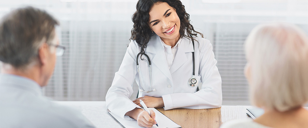 A doctor smiling at two people