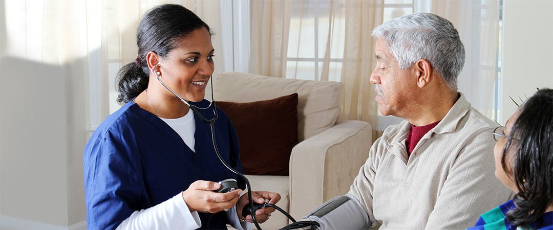 A nurse checking an elderly man's blood pressure