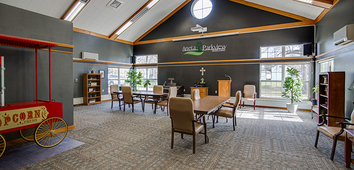 Spacious greeting room with long tables and chairs. Multiple windows allow lots of sunlight.