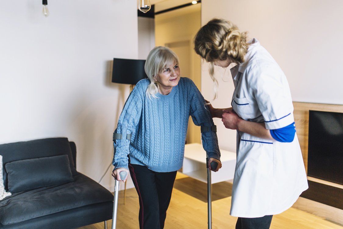 doctor helping woman on crutches