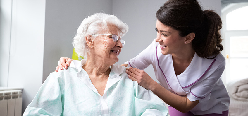 A nurse and patient smiling at each other.